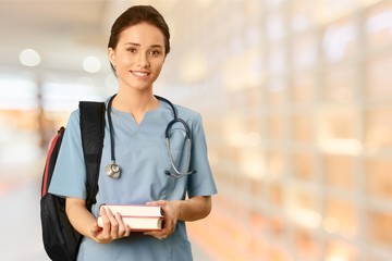 Attractive young female medical student with backpack and books