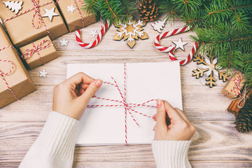 Many envelopes tied with rope. Close-up top view of famale hands with envelope. Pine cones and christmas decoration on old rustic vintage wooden table, desk