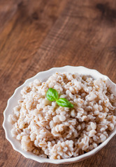 cooked pearl barley in bowl on a wooden table background