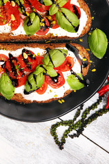 Bread with cream cheese and tomato for lunch table. Sharing antipasti on party or summer picnic time over wooden rustic background