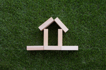 House sharp from wood block on green grass background, Home icon or sign concept