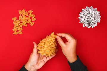 How to make a Christmas tree from raw pasta bows. The process of making Christmas trees from pasta,...