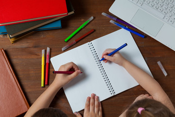 Children do homework at the table. Kids draws on a blank sheet of paper. Preschoolers do homework together. Boy and girl writing a letter.