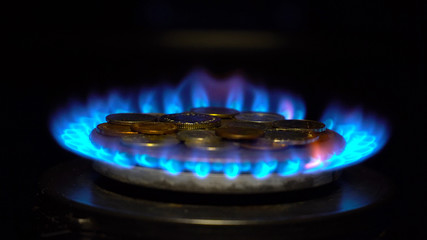 Coins of different countries on a gas burner. Symbol of increasing fuel prices.