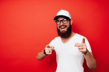 Excited man standing over red wall and pointing at the camera
