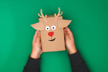 The original design of a Christmas gift from craft paper in the form of a deer on a green...