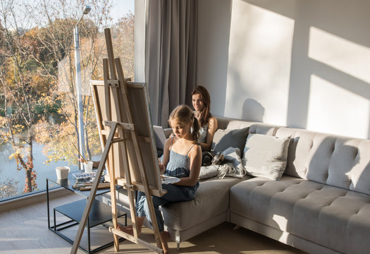 Woman with laptop and girl drawing painting