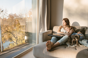 Embracing woman and girl on couch with dog