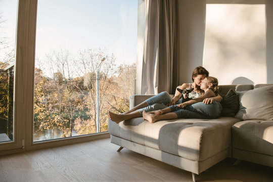 Embracing Woman And Girl On Couch With Dog