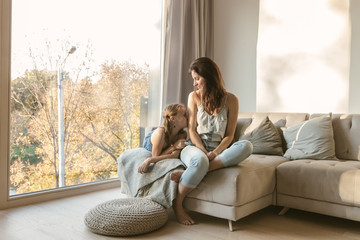 Caressing mother and daughter on couch
