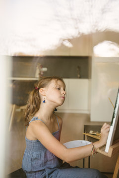 Little girl drawing on canvas at home