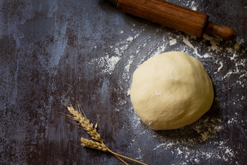Dough. Fresh raw dough ball for bread or pizza on a dark table, baking background. Top view flat...
