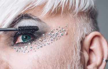 More beautiful lashes. Transgender man wear eyeshadows and eyebrow makeup. Male makeup look. Transgender man apply mascara. Fashion male eye makeup. Male makeup artist