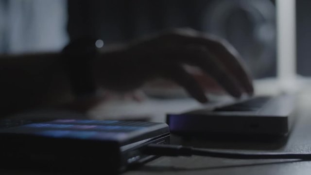 Close up on producer. /musician hand hitting the drum pad and playing a melody riff on MIDI keyboard in the studio