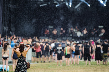 Girl preparing to go on concert on rain, music event in background