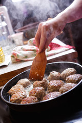 Fried meat patties are cooked in a pan in the oil in the kitchen with steam