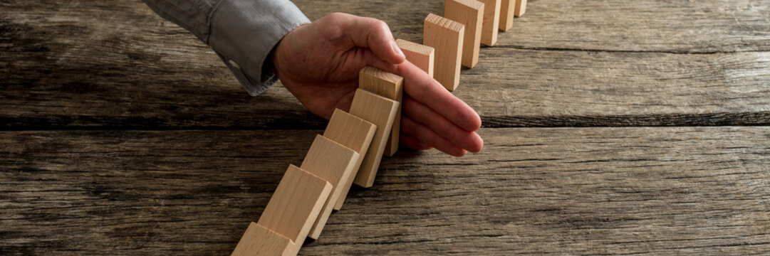 Wide view image of businessman stopping domino effect