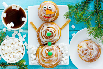 Cinnamon rolls snowman - fun idea for kids breakfast for winter holidays, homemade cinnamon rolls swirl buns stuffed with cinnamon sugar and cream cheese frosting