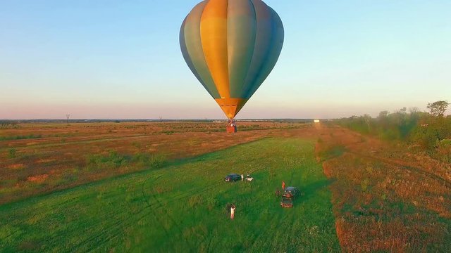 Air Balloon in flight at sunset, takeoff air balloon at sunset, air balloons start fly from grass field at summer sunset