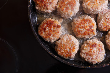 Fried meat patties are cooked in a pan in the oil in the kitchen with steam