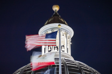 Night view of the US and the California state flag waving in the wind