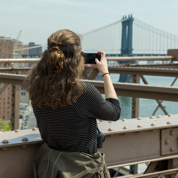 Woman taking a picture on Brooklyn Bridge, Manhattan, New York City, New York State, USA