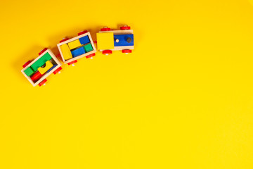 Wooden toy train with colorful blocks on yellow background