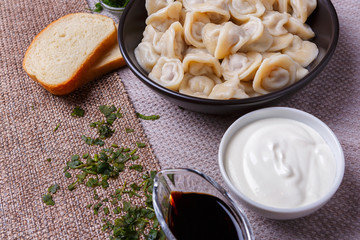 boiled dumplings national dish of many nations with sour cream, soy sauce and greens on the table