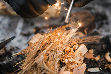 Male hand starts fire with magnesium fire steel, fire striker