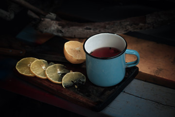 tea with lemons in a rustic forest style on wooden background with old knife and wooden cutting Board