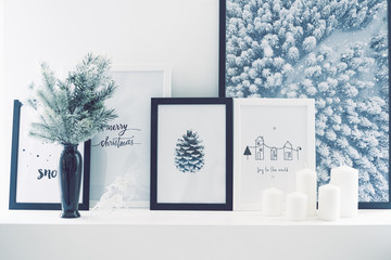 Christmas frames are next to a decorative Christmas tree and candles on the windowsill.