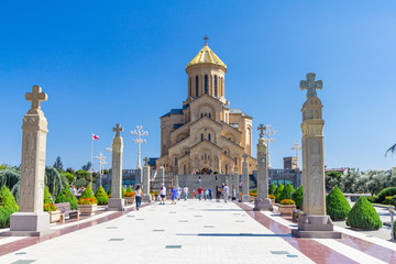 Fototapeta na wymiar Main view with the stair case and cross pillars columns to Tbilisi Sameba Cathedral Tsminda Holy Trinity biggest church Orthodox in a sany day in Caucasus region. The main cathedral of the Georgian.