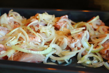 Sliced chicken with onions on a baking sheet. Close-up. Background.
