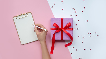 Female writing wish list near christmas gift. Copy space.