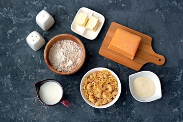 Ingredients for the preparation of macaroni and cheese: dry pasta, orange cheddar cheese, wheat flour, bread crumbs, milk, butter, salt, pepper