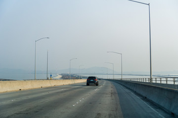 Travelling on Dumbarton bridge towards east San Francisco bay area; smoke and pollution in the air from nearby wildfires; Silicon Valley, California