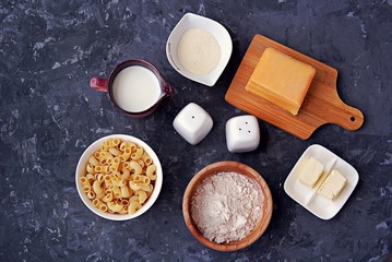 Ingredients for the preparation of macaroni and cheese: dry pasta, orange cheddar cheese, wheat flour, bread crumbs, milk, butter, salt, pepper