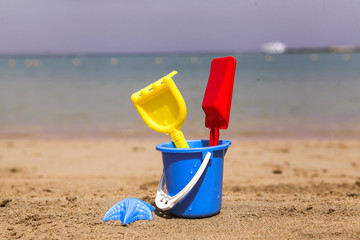Toys on sandy beach in the foreground and blurred sea in the background.