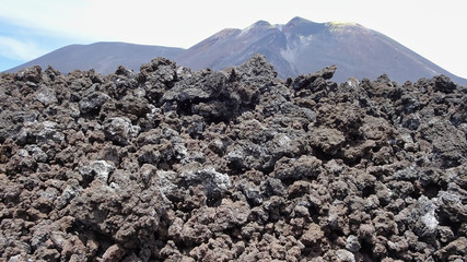 Gesteinsbrocken vom Etna mit Berg im Hintergrund