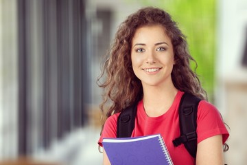 Portrait of a cute young student girl holding colorful notebook