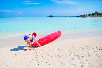 Naklejka na ściany i meble Little girl in Santa hat during beach vacation on tropical vacation
