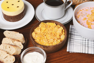 Close up of passion fruit cake, toast, coffee, yogurt, cereals.