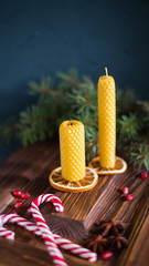 Two extinguished candle, Christmas caramel cane, fir-tree branches on wooden background