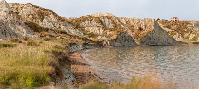 Rocky hill near sea against sky