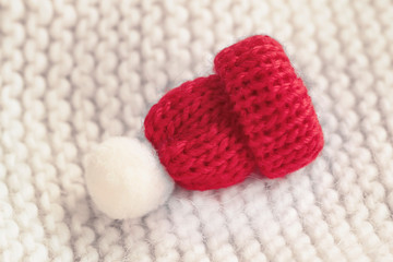 Fototapeta na wymiar Red knitted decorative beanie with pompon on a knitted sweater