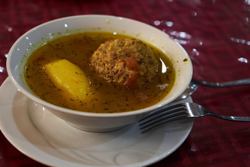 Kufta bozbash soup plate and spoon with fork on table, close-up