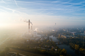 Widok z lotu ptaka na smog nad miastem o poranku, dymiące kominy elektrociepłowni oraz zabudowa...