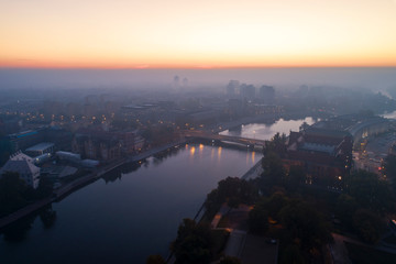Widok z lotu ptaka na smog nad budzącym się miastem o świcie, w dali budynki okryte mgłą i...