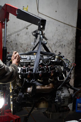 Car engine on crane hook in garage repair service, indoor