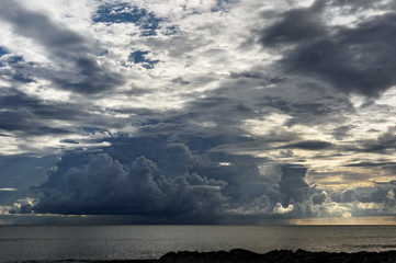 Obraz premium View from a tropical beach to a threatening big dark cloud formation, from which rain falls - Location: Seychelles